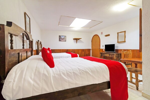 A hotel room with a wooden bed, a television, and a wooden desk.