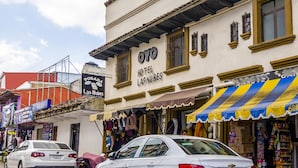 Un hotel llamado "OYO Hotel Las Nubes" con un letrero, una fachada con diversos artículos y un coche estacionado.