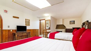 Habitación de hotel con una cama grande, un televisor sobre un aparador de madera y una escalera que sube a un nivel superior.