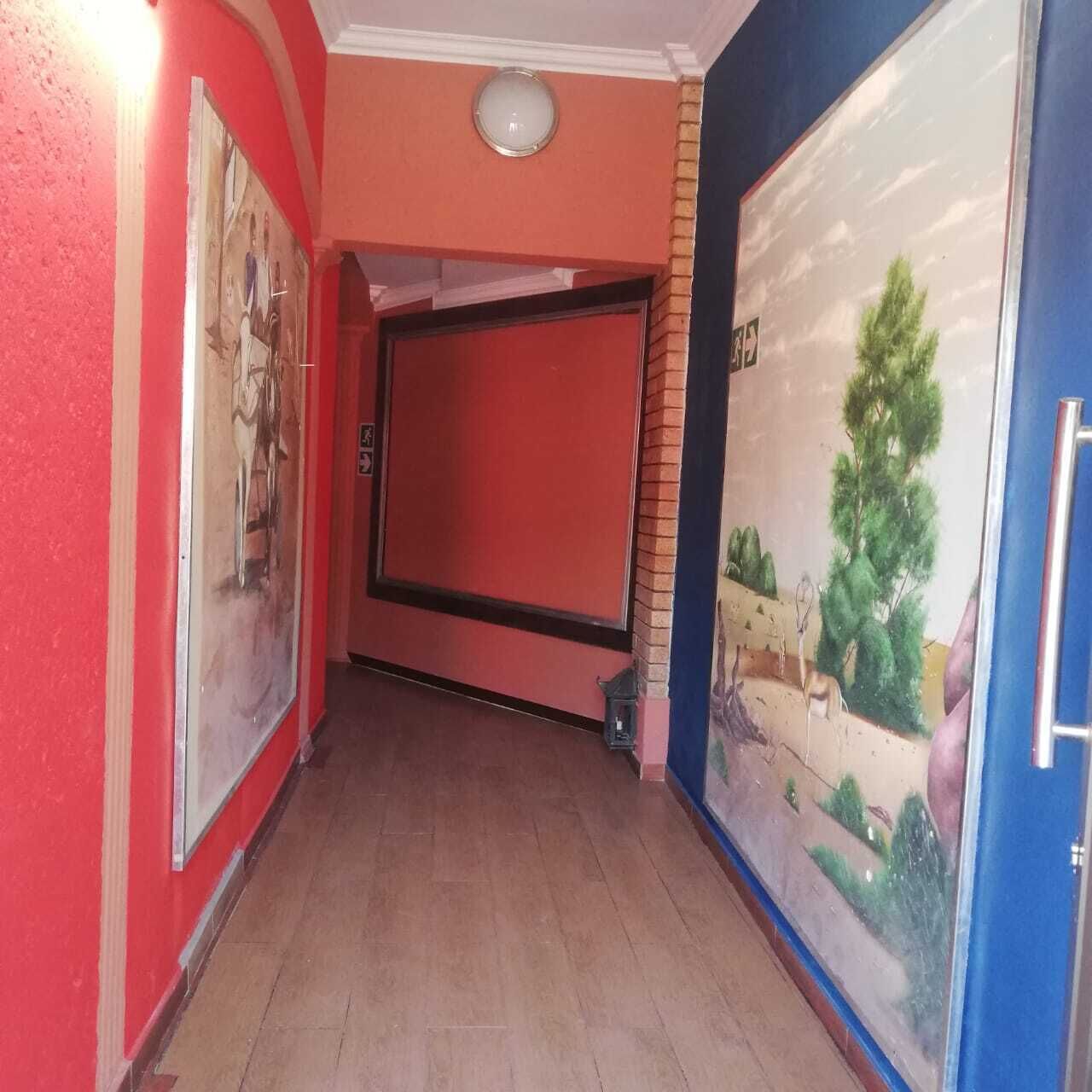 A hallway with red walls, a tiled floor, and a door with a landscape painting.