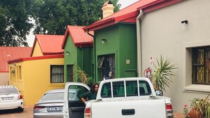 A white pickup truck parked in front of a building with a green door and a red roof.