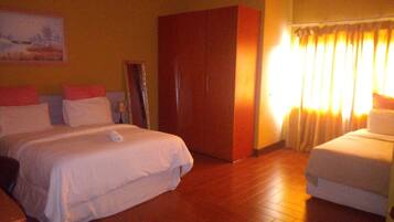 A hotel room with a large bed, a smaller bed, a wardrobe, and a painting on the wall.