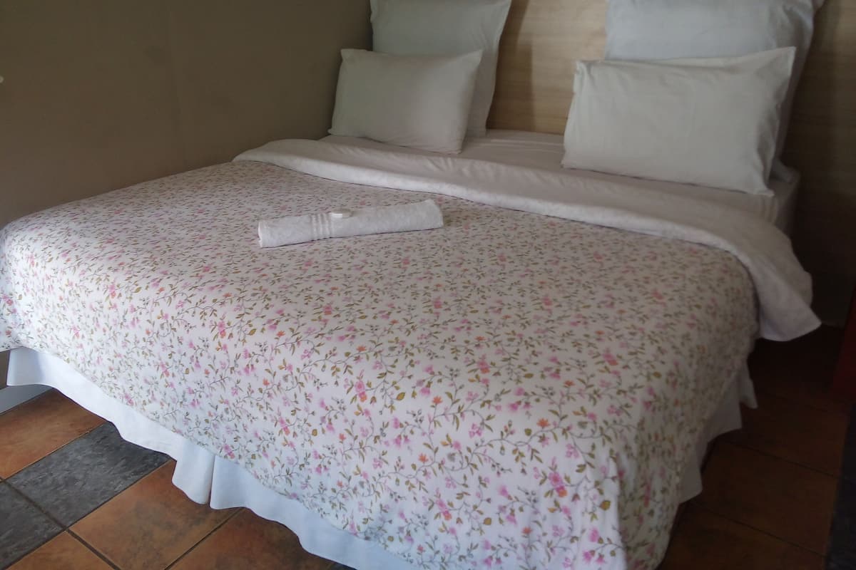 A neatly made bed with floral bedding, white pillows, and a wooden headboard.