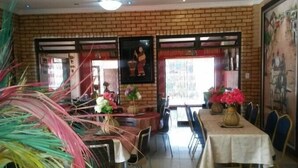 A restaurant with brick walls, framed artwork, and tables set with flowers.