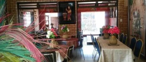 A restaurant with brick walls, framed artwork, and tables set with flowers.