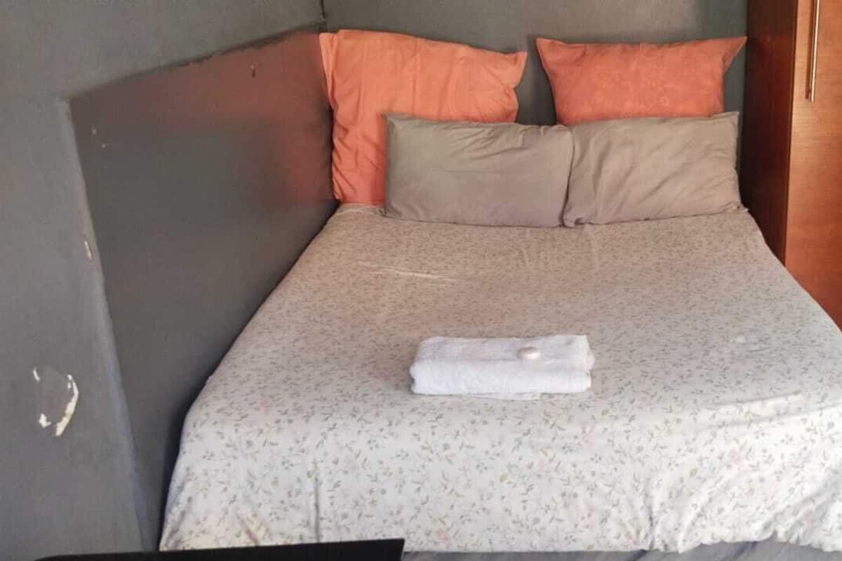 A bed with a floral bedspread, two pillows, and a folded towel.