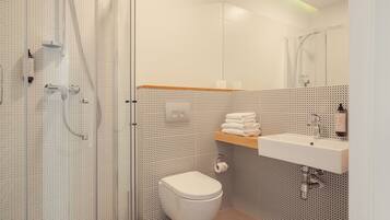 A modern bathroom with a shower, toilet, and sink.