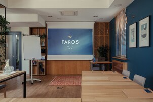 A hotel reception area with a large screen displaying the hotel name, a reception desk, seating area, and a bookshelf.