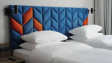 Habitación de hotel con cabecera moderna, ropa de cama blanca y mesita de noche de madera con un control remoto.