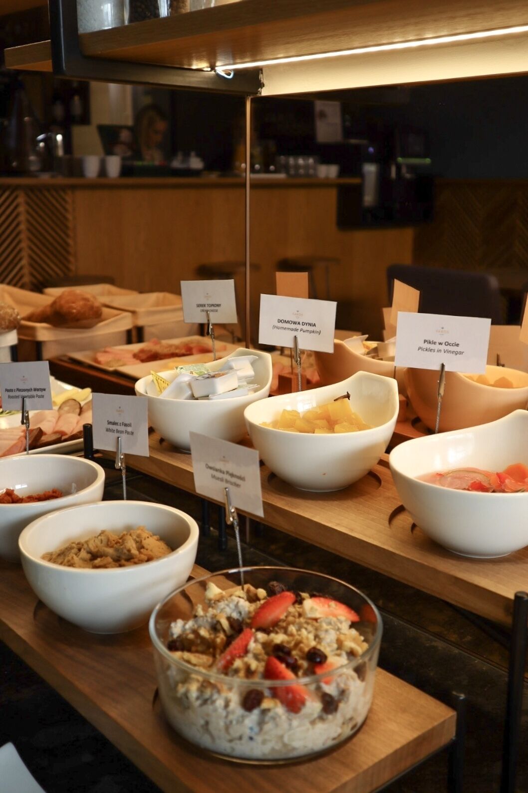 A buffet with various food items labeled, including 'Domowa Dynia (Homemade Pumpkin)' and 'Pikle w Ocie (Pickles in Vinegar)'.
