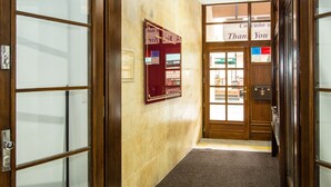 A hotel lobby with a marble floor, wooden doors, a reception desk, and a sign that says "Thank You".