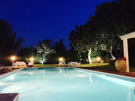 Una piscina al aire libre, sombrillas, sillones reclinables de piscina
