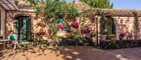 A courtyard with a tiled floor, stone walls, and potted plants.