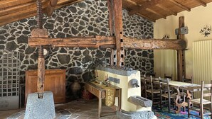 Ein rustikales Interieur mit Steinwänden, Holzbalken, einer Steinguthaube und traditionellen Möbeln.