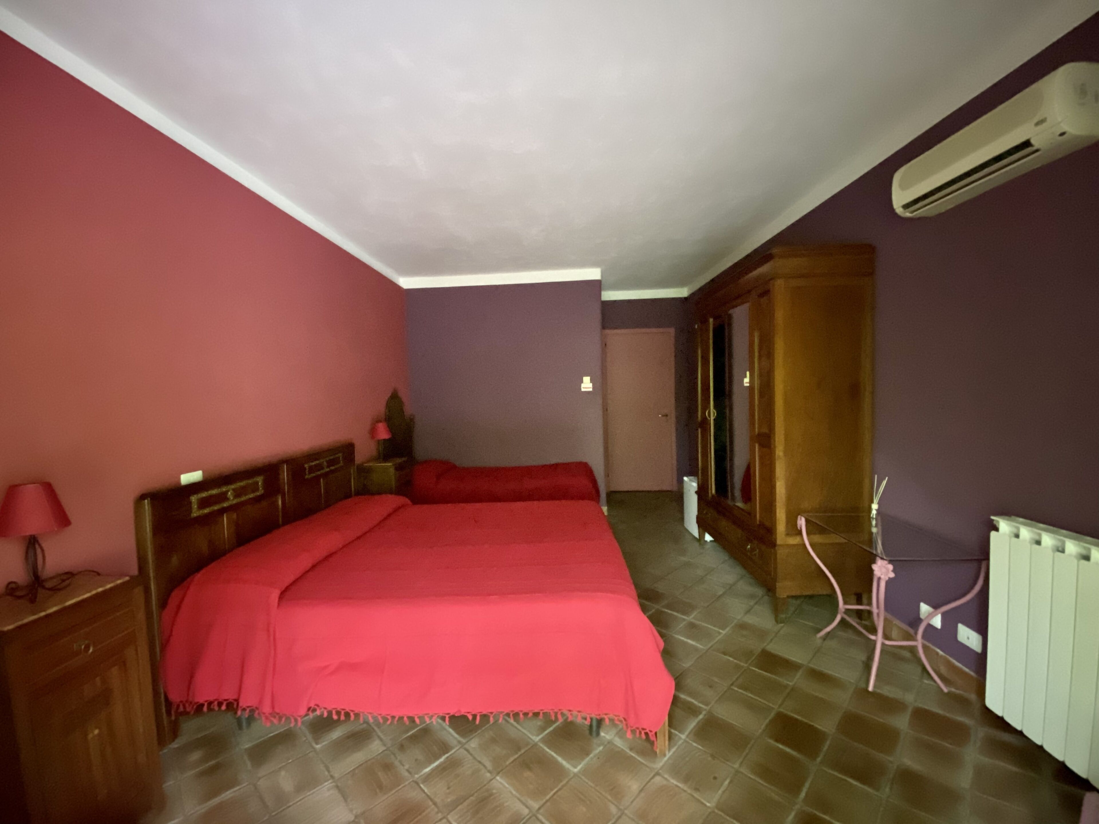 Ein Schlafzimmer mit Bett, Nachttisch, Kommode und Klimaanlage.