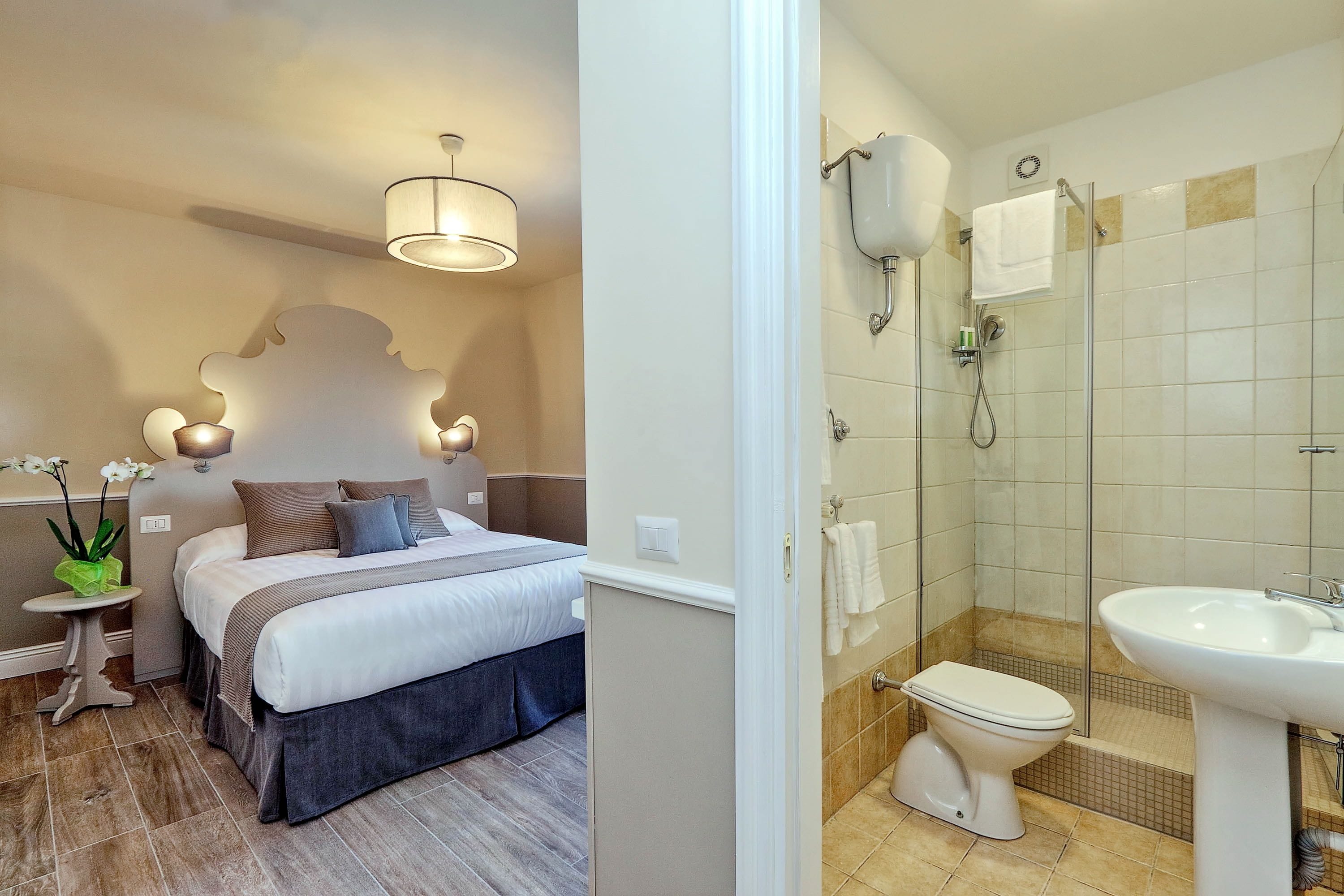A bedroom with a bed, bedside table, and a nightstand with a plant.