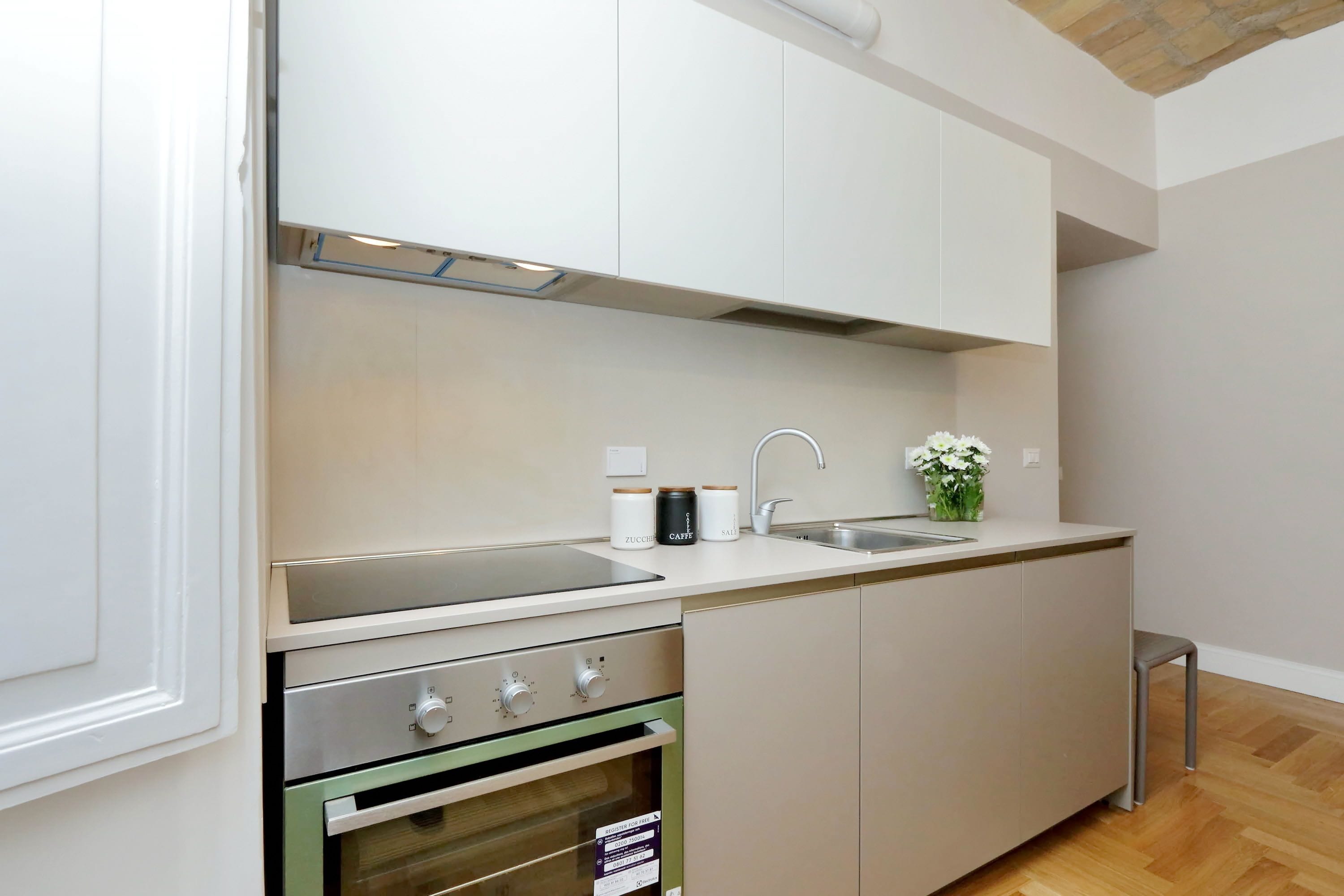 A modern kitchen with white cabinets, stainless steel appliances, a sink, and a small countertop area.
