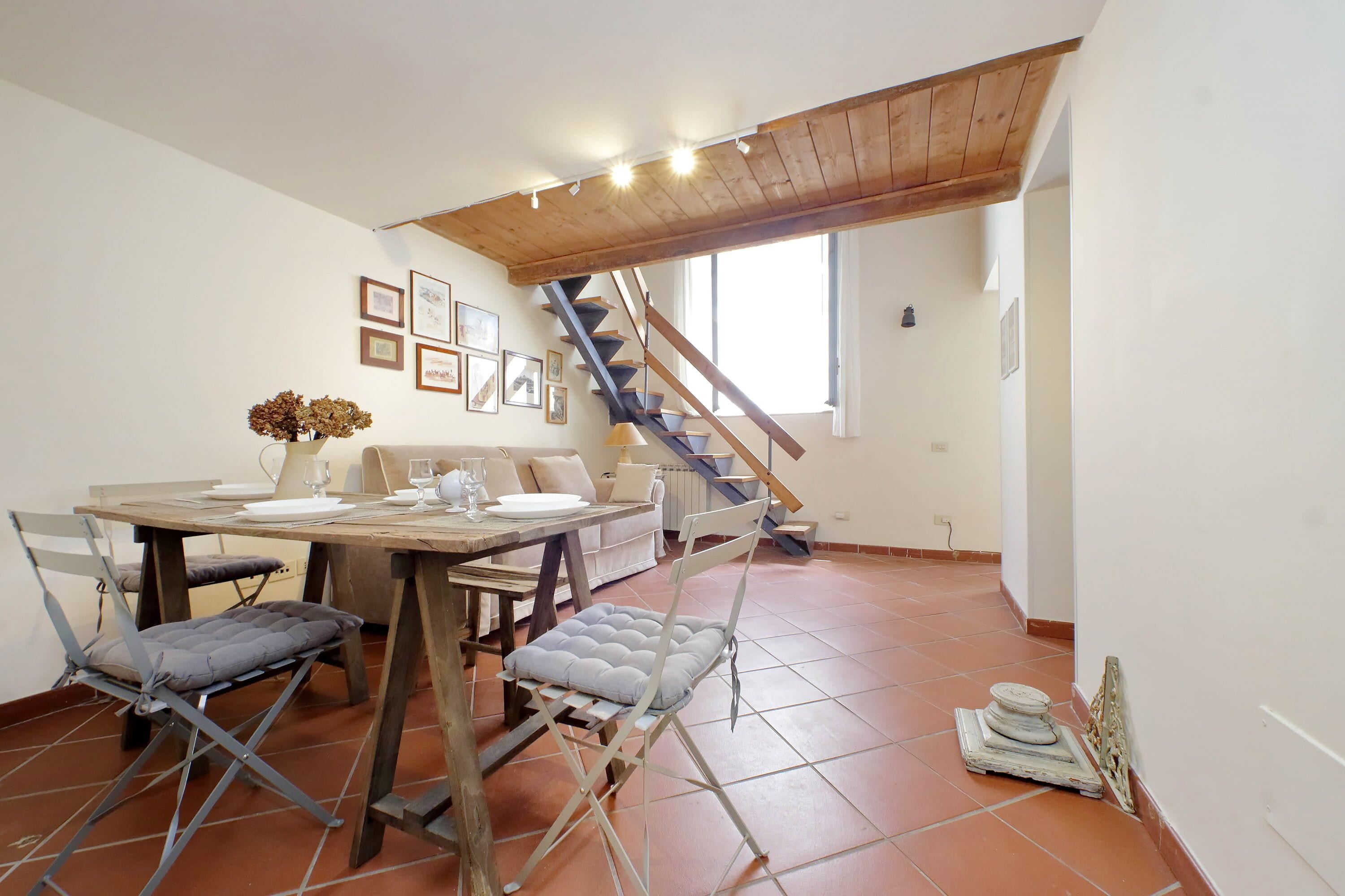Un coin repas avec une table et des chaises en bois, un escalier et un radiateur.