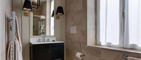 Un baño con un inodoro blanco, un tocador negro con espejo y dos lámparas de pared.