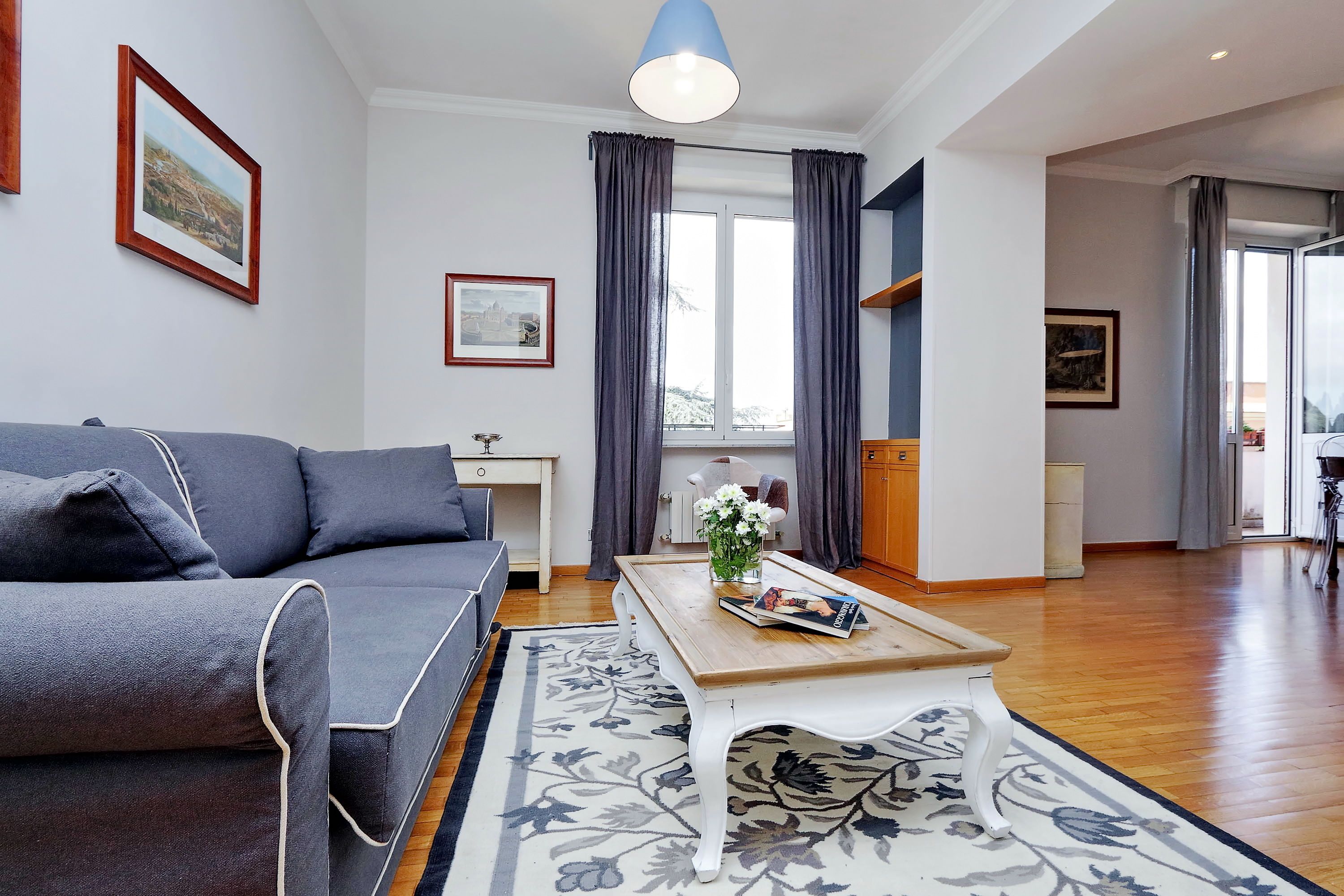 Un salon moderne avec un canapé gris, une table basse en bois et un tapis à motifs floraux.