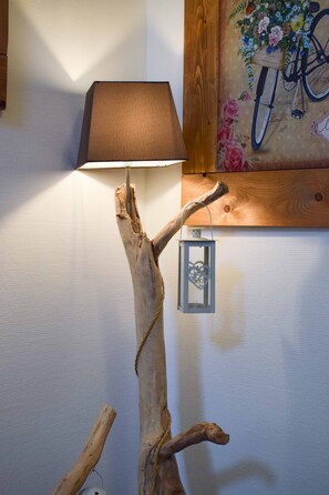 A lamp on a wooden branch structure against a wall with a floral painting. - Hotel Scoiattolo (Falcade)
