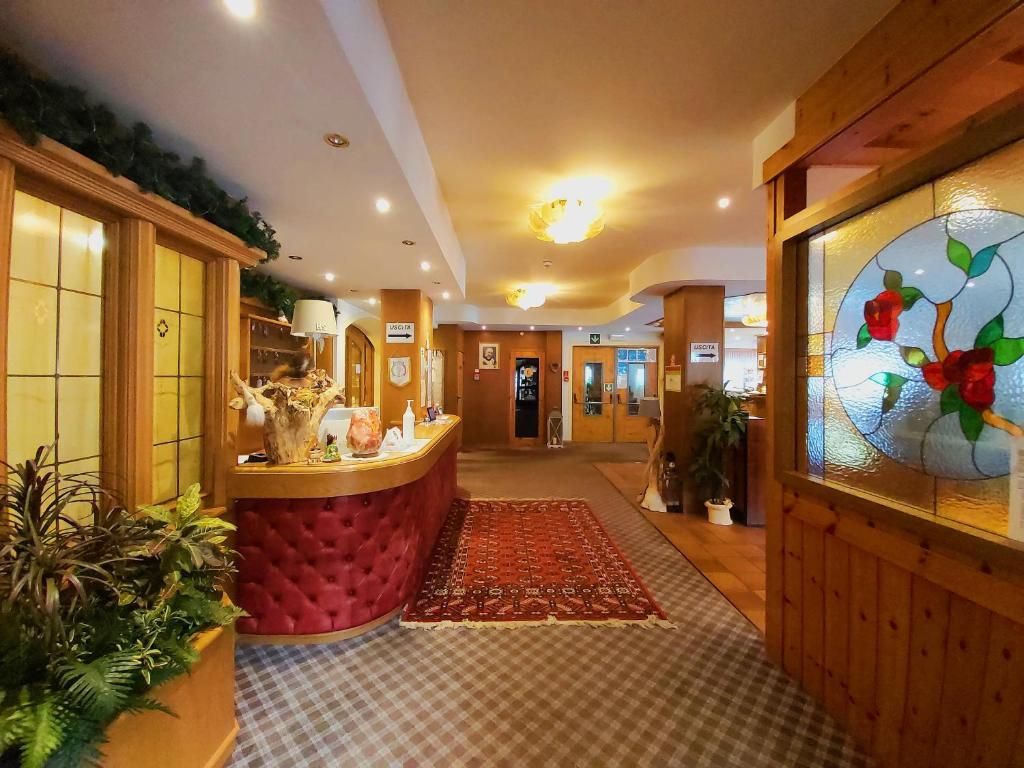 A reception area with a red cushioned counter, a checkered carpet, and a glass wall with a floral design.