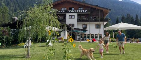A hotel with a wooden facade, a balcony, and a mountain backdrop.