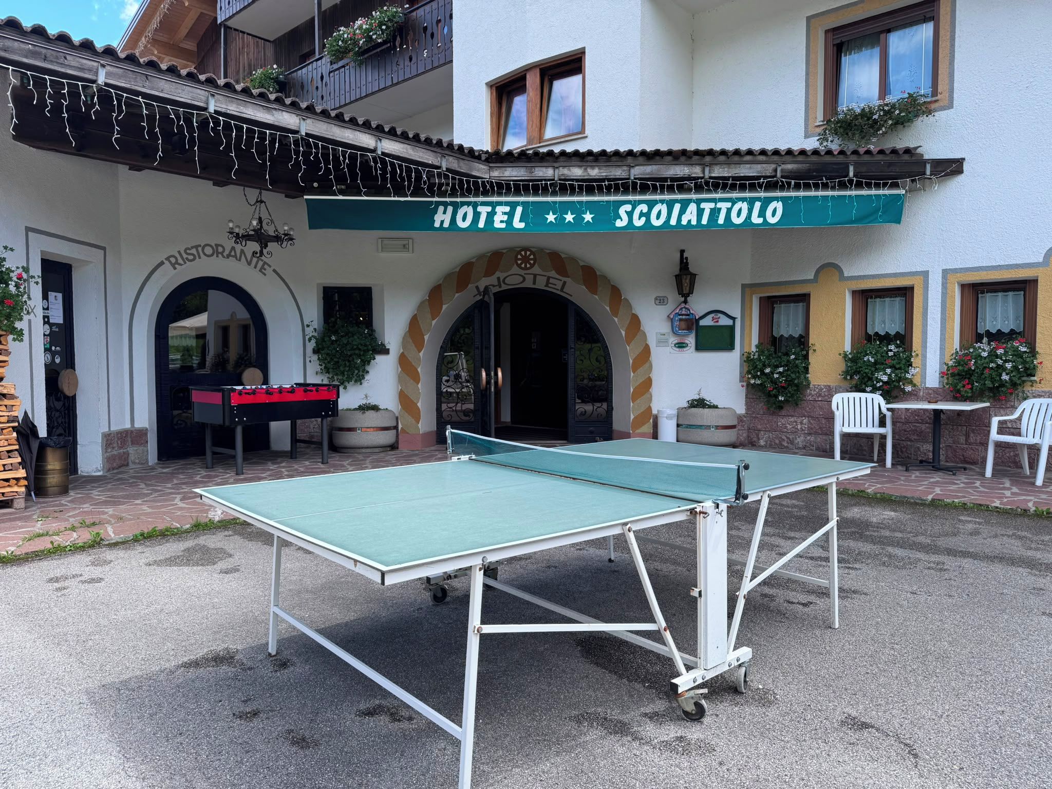 Un hotel chiamato 'SCOIATTOLO' con un tavolo da ping pong nel cortile.