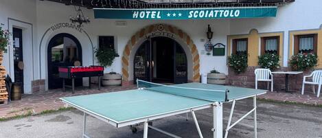 Un hotel llamado 'SCOIATTOLO' con una mesa de ping pong en el patio.