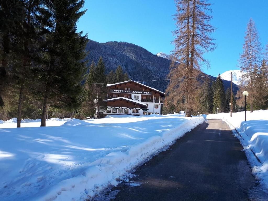 A hotel with a wooden facade, a snow-covered driveway, and a mountain backdrop.