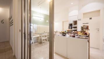A modern kitchen with a central island, white cabinetry, and a breakfast bar with fruit and snacks.