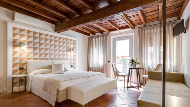 A bedroom with a bed, a bench, a small table, and a sofa. - Ferrara Rooms (Ferrara)