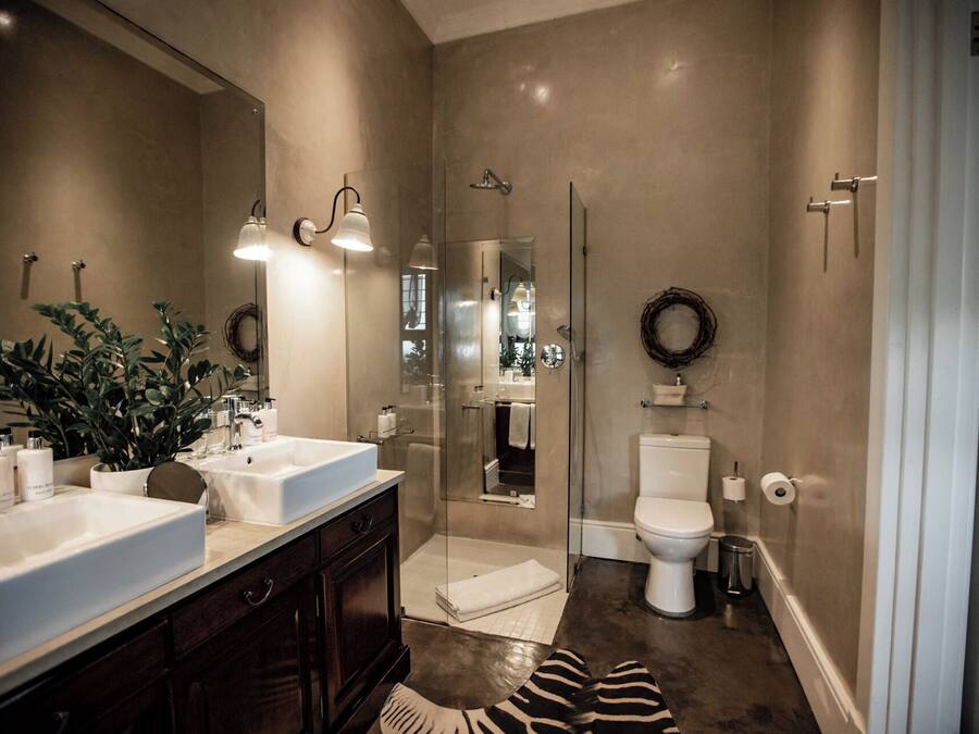 Un baño moderno con un espejo grande, dos lavabos, ducha e inodoro.
