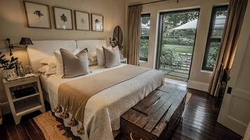 A bedroom with a bed, bedside tables, a wooden bench, and a view of the outdoors.