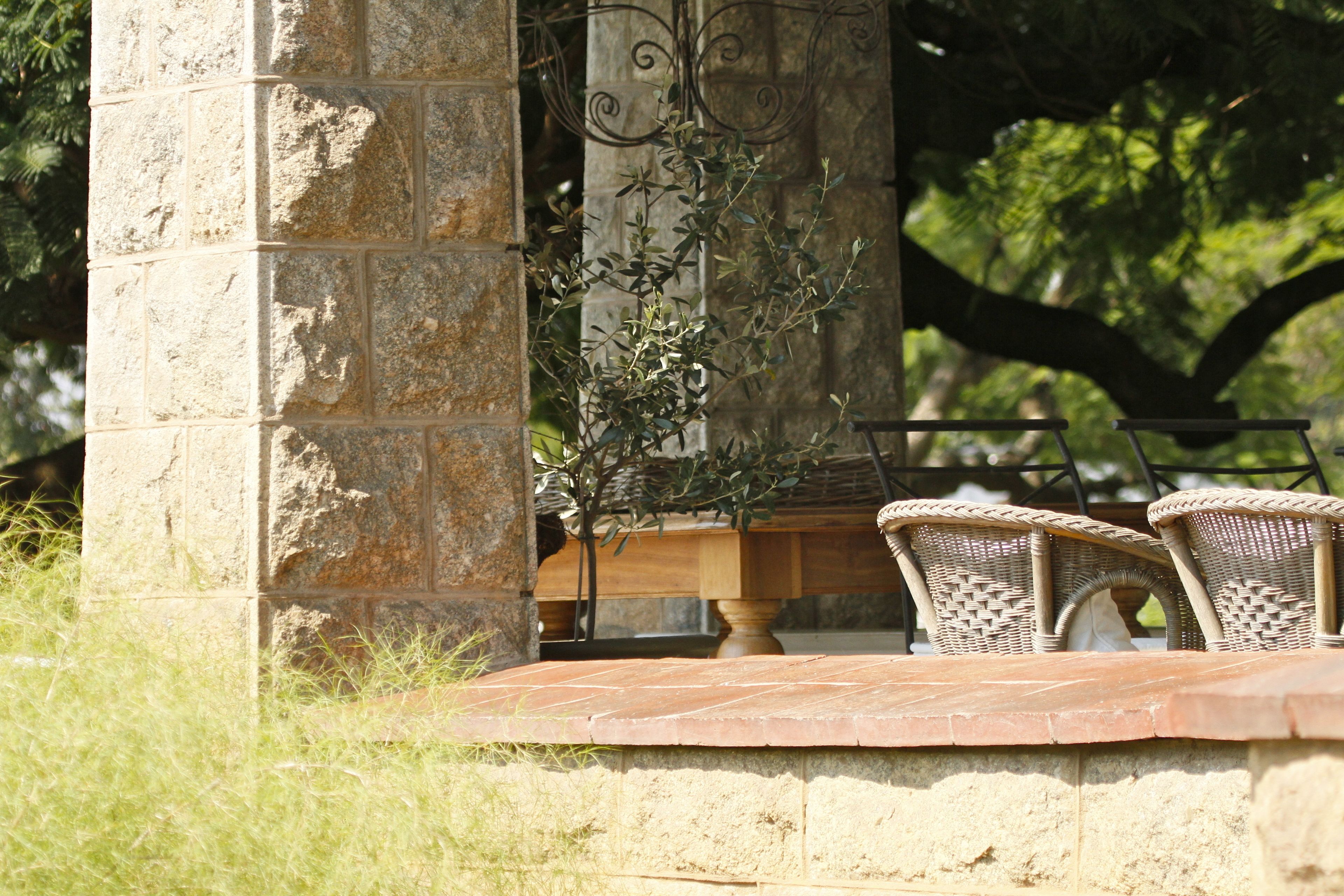 A stone pillar, wicker chairs, and a table with a plant.