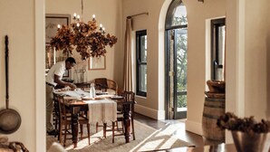 Comedor con candelabro, muebles de madera y ventanas amplias.
