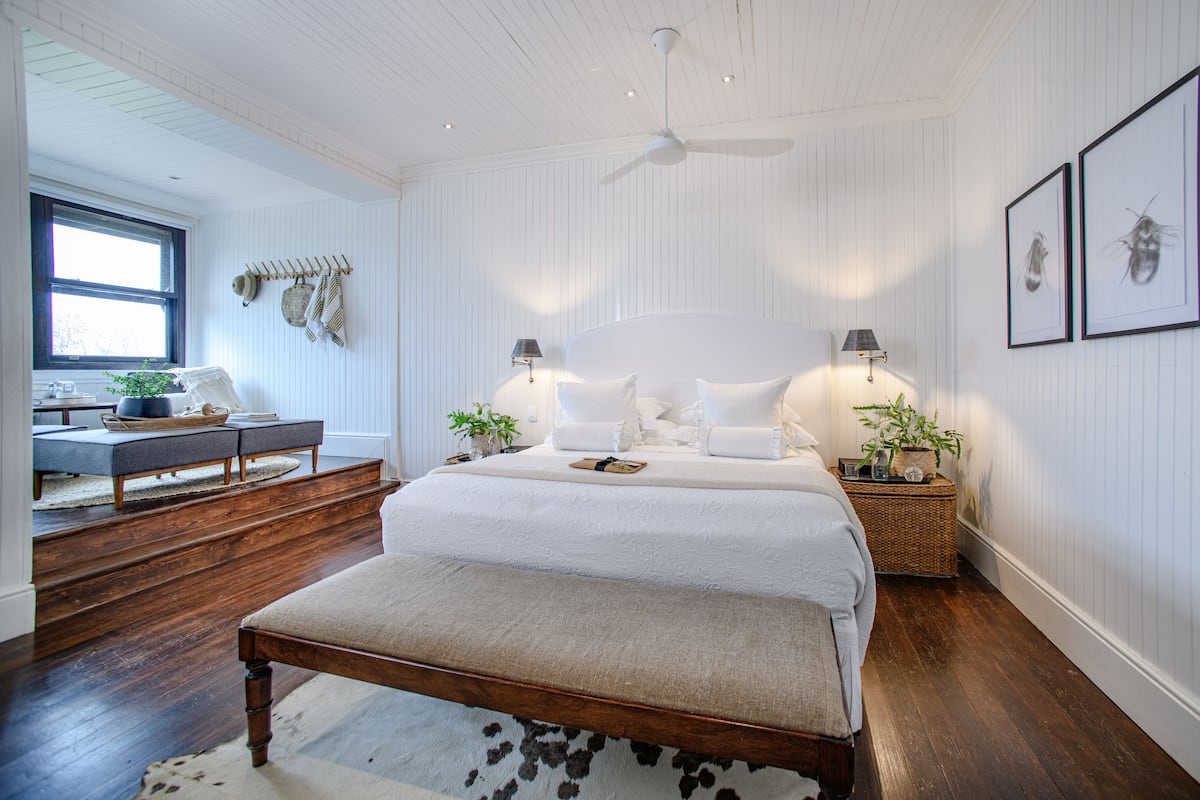 A bedroom with a large bed, bedside tables, a ceiling fan, and a window.