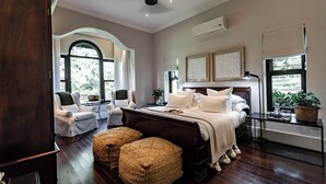 Un dormitorio con una cama grande, dos sillas, un armario de madera y una ventana con vistas.
