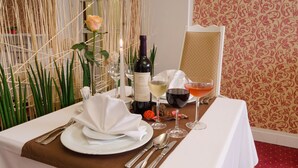 Una mesa preparada para comer, con una botella de vino, copas y una rosa.