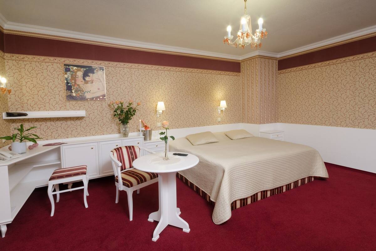 A hotel room with a bed, desk, chair, and a small table.
