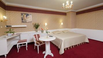 A hotel room with a bed, desk, chair, and a small table.