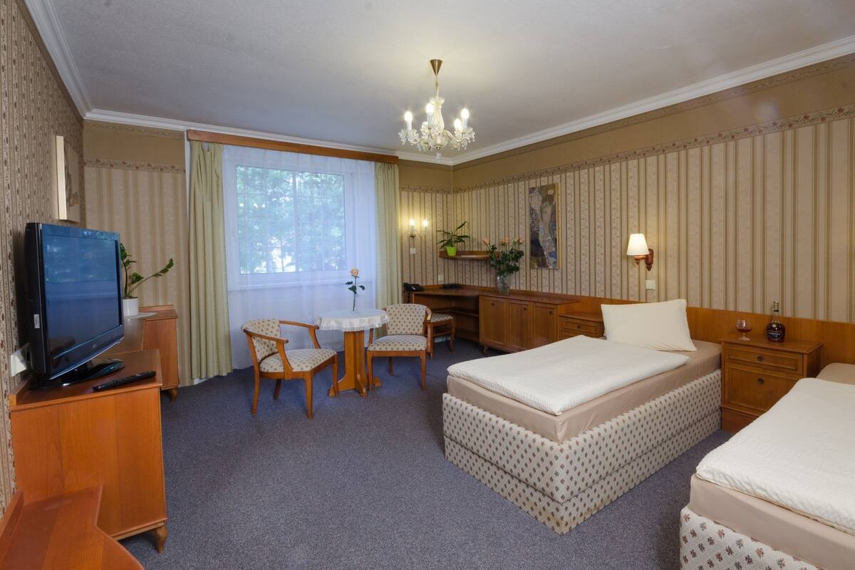 A hotel room with a bed, a desk, a chair, a television, and a window.