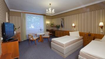 A hotel room with a bed, a desk, a chair, a television, and a window.