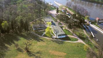 An aerial view of a park with a large building, a boat dock, and a river.