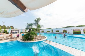 A swimming pool with a circular island, lounge chairs, and a covered area. - Nicolaus Club Alimini Smile  (Otranto)