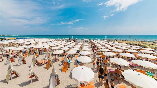 A beach with numerous sun umbrellas and lounge chairs, indicating a beach resort setting. - Nicolaus Club Alimini Smile  (Otranto)