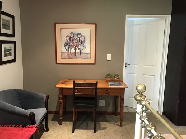 A dining area with a wooden table, chairs, and a framed painting on the wall.