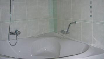 A white bathtub with a handheld showerhead and a built-in faucet.