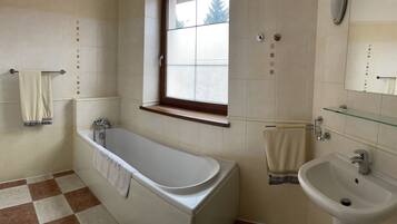 A bathroom with a bathtub, a sink, a window, and a towel rack.