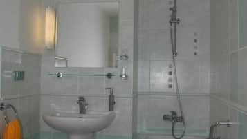 A bathroom with a sink, mirror, and bathtub.